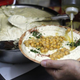 hand pouring olive oil on hummus